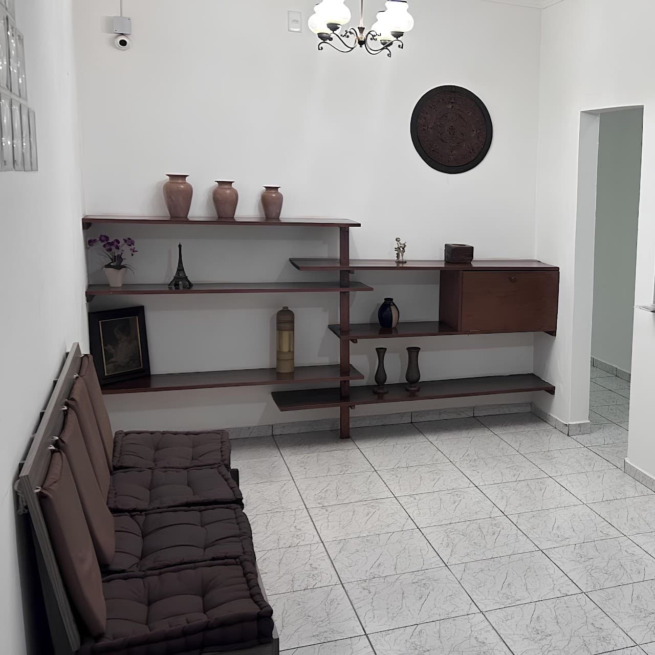 Recepção - sofá com futons marrons e estante em madeira escura com vasos e decoração
